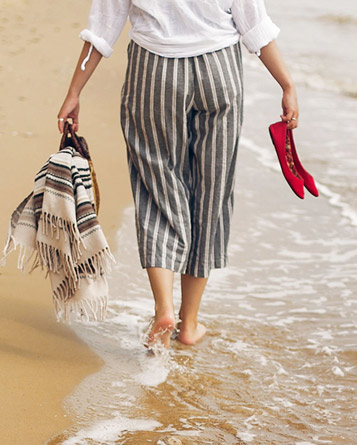 Một người phụ nữ đi bộ bằng chân trần trong nước trên bãi biển